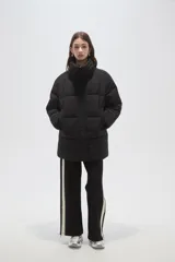 Campera puffer negra de corte holgado, con cuello alto, cierre frontal oculto y bolsillos laterales.