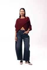 Sweater de punto con diseño cruzado frontal, de silueta amplia y mangas largas con puños ajustados. Presenta un corte holgado y textura suave.