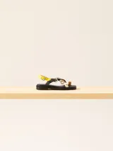 Sandalia baja de cuero vacuno con tiras cruzadas y aplique decorativo. Tiene hebilla en el talón y empeine para regular el calce.