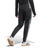 Pantalón de jogging negro con tres rayas blancas a los costados y logo de Adidas en la pierna izquierda.
