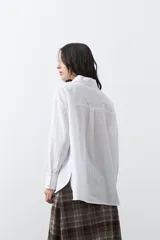 Camisa de corte relajado y diseño clásico, confeccionada en tela de algodón color celeste. Presenta cuello tradicional, cierre frontal con botones y mangas largas con puños rectos.