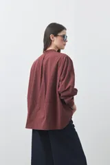Camisa de manga larga en color celeste, con cuello mao y cierre frontal oculto. Presenta un diseño de silueta relajada con sisa caída y un bolsillo aplicado en el pecho.