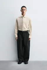 Camisa de corte relajado confeccionada en algodón, con estampado de rayas verticales. Presenta cuello solapa, manga larga con puños abotonados, bolsillo frontal y corbata integrada del mismo tejido.