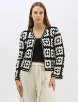 Cardigan abierto de tejido de punto calado con diseño geométrico y floral bicolor. Presenta escote en V, mangas largas y cierre frontal con tiras para anudar. Incluye detalles de vivos a contraste en el contorno del escote, puños y ruedo.