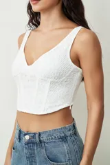 Top blanco de encaje con diseño estilo corsé, escote en V y tirantes anchos.