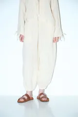 Pantalón abullonado color beige, de tiro alto con cintura elástica y cordón ajustable. Tiene bolsillos laterales y puños elásticos en los tobillos.