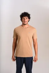 Remera de manga corta con cuello redondo, confeccionada en algodón de color beige. Presenta un pequeño logo bordado de un pingüino en el pecho.