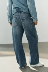 Jeans de tiro medio con diseño baggy, de pernera ancha y corte holgado. Cuenta con cinco bolsillos, trabillas para cinto y cierre frontal con cremallera y botón metálico.