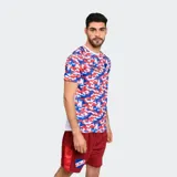 Remera deportiva Umbro de entrenamiento del Club Nacional de Football, con estampado de camuflaje en tonos rojo, blanco y azul. Presenta cuello redondo y el escudo del club en el pecho.
