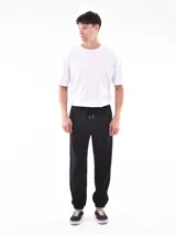 Pantalón jogger negro de felpa, con cintura elástica ajustable mediante cordón y puños elásticos en los tobillos.