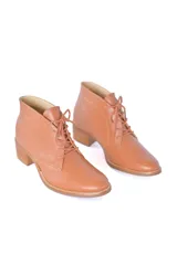 Botines de cuero vacuno color caramelo con diseño clásico de caña baja, cordones frontales y puntera redondeada. Presentan un tacón bloque texturizado de altura media.
