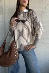 Sweater de punto con diseño abstracto de líneas orgánicas en tonos gris y beige, cuello redondo, manga larga con puños ajustados y corte holgado.