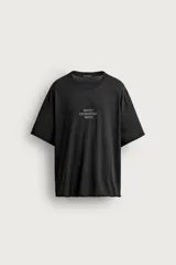 Camiseta de corte relaxed fit color negro, confeccionada en tejido ligero con mezcla de algodón y lino, con cuello redondo, manga corta y efecto lavado. Presenta estampado de texto en el frente.