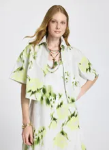 Camisa corta de mangas cortas con estampado abstracto en tonos verde y amarillo sobre fondo blanco.