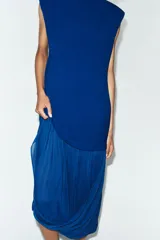 Vestido midi de color azul eléctrico con cuello subido y diseño sin mangas. Presenta un cuerpo liso y una falda con caída fluida y detalle de tul en el bajo.