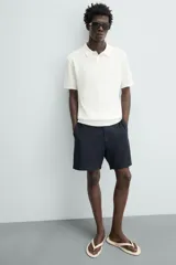 Bermuda azul marino de corte regular fit, confeccionada en tejido de algodón y lino. Cuenta con bolsillos frontales y traseros, cierre frontal con cremallera y botón.