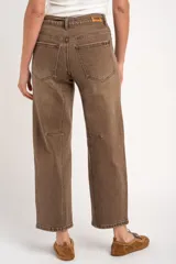 Jean barrel tiro alto en color marrón, confeccionado en denim con lavado artesanal. Presenta corte amplio en las piernas, bolsillos clásicos y un lazo fino desmontable en la cintura.