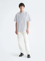 Camisa de manga corta para hombre, color blanco con rayas verticales finas en tonos azul y gris oscuro. Presenta cuello clásico y corte relajado (relaxed fit).