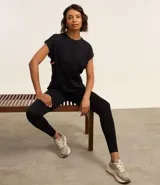 Remera deportiva negra de microfibra de poliamida, con cuello redondo, mangas cortas y franja lateral contrastante color naranja.