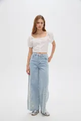 Pantalón jean de tiro alto y corte ancho, color celeste, con delicados bordados de flores blancas en la parte inferior de las piernas.