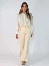 Camisa de corte oversize y diseño holgado, con cuello camisero, cierre frontal de botones y mangas largas con puños abotonados. Presenta un ruedo redondeado y una caída fluida.
