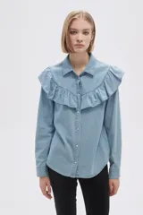 Camisa celeste de jean con cuello clásico, cierre frontal con botones y volados en el canesú delantero y trasero.