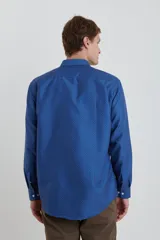 Camisa azul con microestampado de lunares blancos, de corte clásico, con cuello abotonado y manga larga.