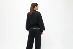 Conjunto compuesto por una chaqueta bomber de estilo híbrido con paneles frontales de denim y mangas de algodón, y un pantalón de jogging de corte recto en color negro.