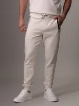 Pantalón de jogging color crema con cintura elástica ajustable con cordón, bolsillos laterales con cierre y puños ajustados.