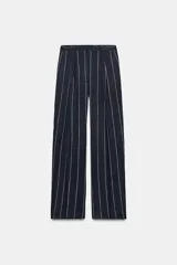 Pantalón de tiro medio de ZARA Woman Collection, confeccionado con mezcla de lino. Presenta diseño de rayas diplomáticas, bolsillos laterales, pinzas en el delantero y cierre frontal con cremallera, botón y ganchos metálicos.