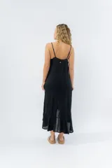 Vestido negro midi con tirantes finos y escote en V. Diseño fluido con bajo asimétrico.