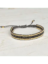 Pulsera tejida con cuentas Miyuki originales en tonos negro y dorado, con terminación de dos cuentas en acero dorado.