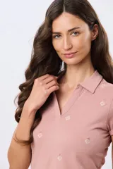 Remera polo de algodón color beige con mangas cortas, escote en V y cuello camisero. Presenta delicados mini bordados florales distribuidos en toda la prenda.