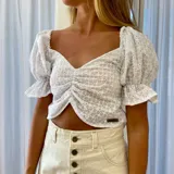 Blusa corta blanca de algodón bordado con mangas abullonadas y escote cuadrado con fruncido central.