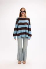 Buzo de tejido de punto con diseño de rayas horizontales anchas en color amarillo y marrón. Presenta cuello redondo, corte holgado y detalle de aberturas en los hombros.