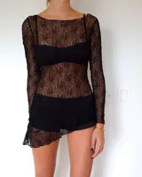 Vestido corto de encaje negro con diseño asimétrico en el ruedo. Presenta mangas largas y un corte ajustado, con un estilo que combina transparencia y texturas.