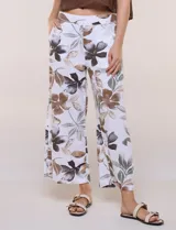 Pantalón crop de lino y rayón, con diseño wide leg de corte holgado, estampado tropical de hojas en tonos verde, azul y marrón sobre fondo blanco. Cuenta con pretina trasera elastizada y bolsillos delanteros.