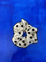 Colita de pelo tipo scrunchie de tela satinada color crudo con estampado de lunares negros y borde con costura en contraste.