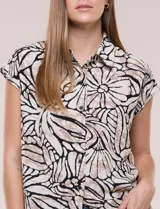 Túnica de gasa negra con estampado floral en tonos azules y blancos, cuello camisero, manga corta y cierre frontal de botones.