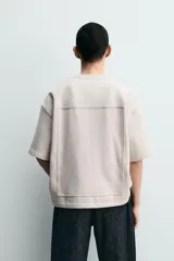 Sudadera de corte relajado confeccionada en tejido de algodón, con cuello redondo y manga corta. Presenta una aplicación de parche combinado a tono en la parte frontal y trasera.