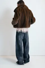 Abrigo corto de efecto pelo en color marrón, con cuello solapa, manga larga y bolsillos laterales. Cuenta con forro interior a tono y cierre frontal mediante ganchos metálicos.
