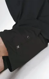 Short de baño negro de calce regular, confeccionado en textil plano liviano de secado rápido. Cuenta con cintura elástica con cordón ajustable, cuatro bolsillos y detalles de ojalillos metálicos laterales.