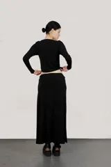 Top negro de mangas largas con escote bote y trenza de terciopelo en el cuello.