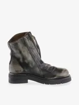 Bota corta de cuero bovino, color negro con efecto desgastado o metalizado grisáceo. Presenta cierre lateral con tirador y suela gruesa de goma con relieve.