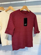 Sweater de tejido de punto con textura de ochos, color blanco, de cuello redondo y mangas cortas.