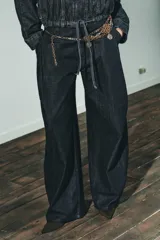 Cinturón de múltiples cadenas metálicas en tonos dorado envejecido y plateado. Presenta secciones de malla con diseño de rombos y dijes colgantes con grabados oscurecidos.