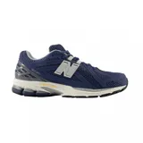 Championes urbanos New Balance modelo 1906R, color azul marino con detalles en gris y blanco. Confeccionados con una combinación de malla técnica y paneles sintéticos, presentan el logo 'N' característico en los laterales y una entresuela con tecnología de amortiguación.