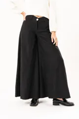 Pantalón de corte palazzo en color negro, con cintura alta, cierre frontal con botón y costuras verticales que definen su estructura amplia.