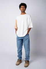 Remera de corte oversize en color beige, con cuello redondo en contraste negro y una manga en color negro. Presenta un pequeño estampado circular en el pecho con la frase 'Don't worry, be happy'.