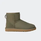 Botas cortas de gamuza color verde oliva, con interior forrado en piel de oveja y suela de goma color tostado. Presentan un diseño clásico de caña baja con etiqueta de cuero en el talón.